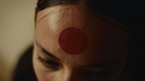 Close-up of a person with a red circle on their forehead