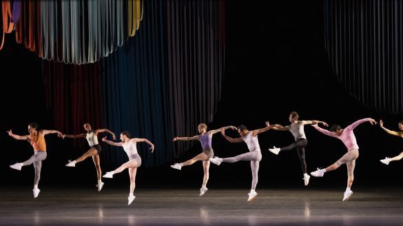 Several dancers lifting their right arms and legs toward stage left, wearing sportwear.