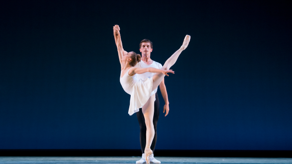 One ballet dancers wears a white tulle dress and the other wears a white shirt and black pants.