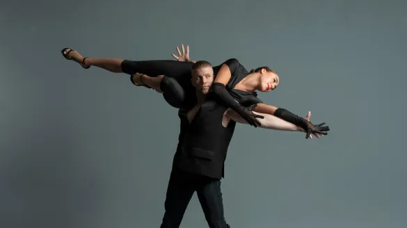 A male dance carries another dancer over his shoulders. The other dance extends horizontally.