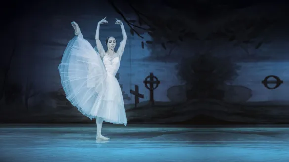 A ballerina pirouettes on a dark and gloomy stage.