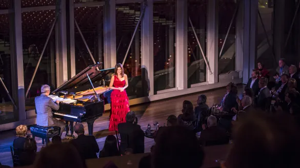A pianist and singer on the Pritzker stage in front of an audience.