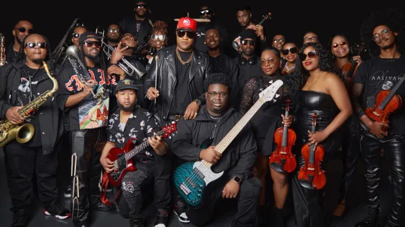 A large group of people posing together with their instruments.