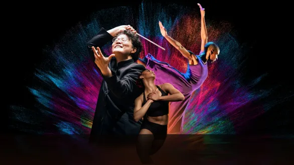 Maestra Mei-Ann Chen conducting with two dancers from Deeply Rooted Dance Theater in front of a colorful splash and black background.