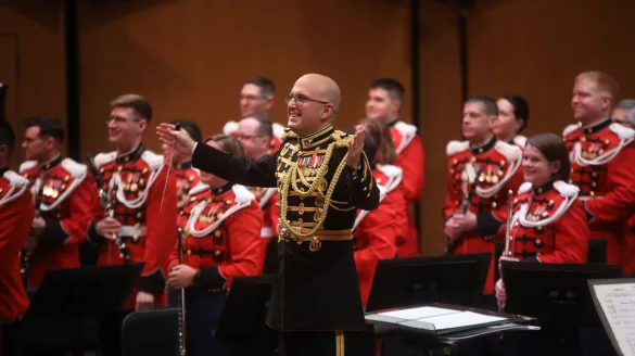 The US Marine band standing and smiling for an audience.