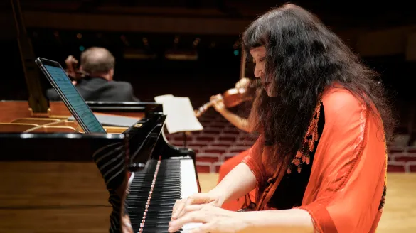 Wu Han playing the piano while other musicians play in the background