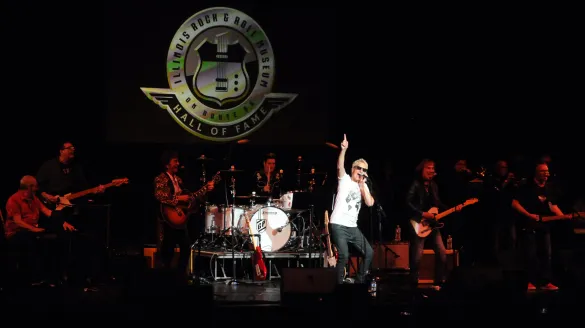 REO Speedwagon’s Kevin Cronin performs onstage with the band beneath the illuminated Illinois Rock & Roll Museum Hall of Fame logo during a live set.