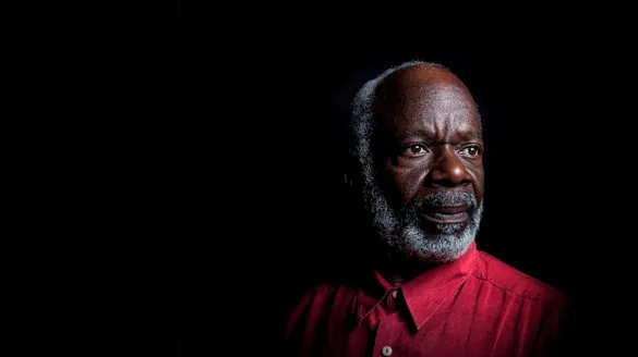 Actor Joseph Marcell in a red shirt on a black background
