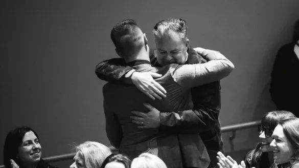 A black and white image of two men hugging at a ceremony