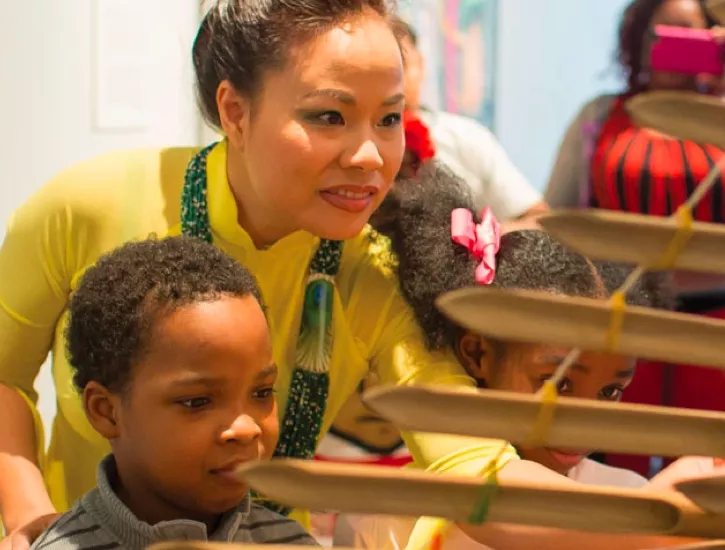 Artist Van-Anh Vo provides a demonstration of Vietnamese music and shows a student the dan t'rung, a traditional Vietnamese instrument.
