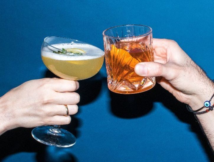 An image of hands clinking drinks together.