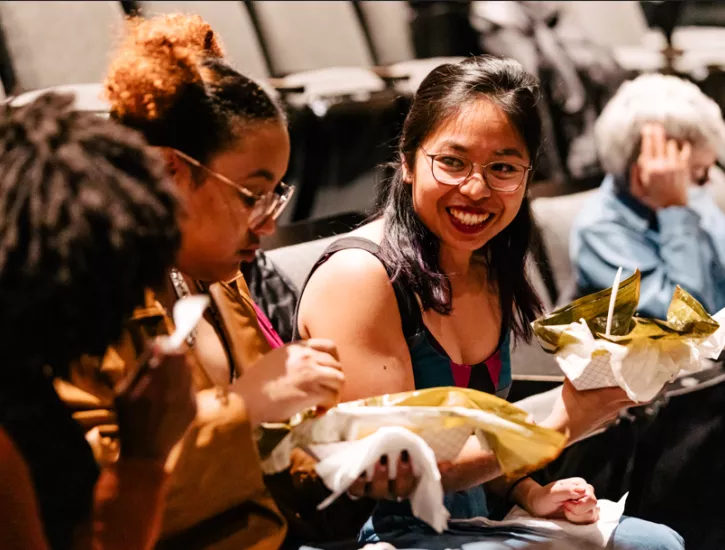 Women sitting smiling and enjoying tamales. 