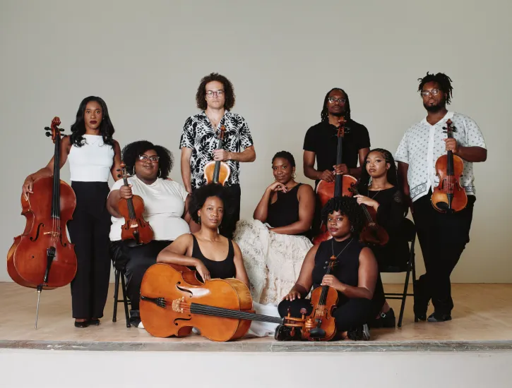 D-Composed posing on stage with their instruments.